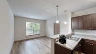 Located at 200 Citygreen Way in Chattanooga, Tennessee, this one-bedroom, one-bathroom residence offers a thoughtfully designed single-floor layout. The kitchen is a standout feature, showcasing rich dark-wood cabinetry, light countertops, and a full suite of black appliances including a refrigerator, electric range, and built-in microwave. Pendant lighting hangs above a curved breakfast bar peninsula, creating a defined yet open connection to the living area. Wood-look flooring runs throughout the kitchen and living spaces, adding warmth and easy maintenance. The bedroom is a comfortable, well-proportioned retreat finished with plush carpeting and a ceiling fan with light fixture. Multiple windows fitted with blinds allow for natural light and outdoor views, while a door provides direct exterior access. A dedicated closet offers practical storage within the bedroom. The bathroom is clean and functional, featuring a dark-wood vanity with a white countertop and sink, a toilet, and a full bathtub/shower combination. Neutral wall tones throughout the residence create a bright, cohesive atmosphere. The efficient floor plan makes excellent use of space, with each room clearly defined and purposefully arranged.