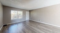 Located at 1345 S Kolb Rd in Tucson, Arizona, this two-bedroom, one-bathroom single-floor unit offers a practical and well-organized layout. The combined living room and kitchen area forms the heart of the home, featuring durable wood-look plank flooring, neutral gray walls, and a textured ceiling throughout. The living room is generously proportioned, with a large window that invites ample natural light and provides views of the surrounding area. A hallway connects the main living space to the rest of the unit. The kitchen is efficiently designed with light wood cabinetry, white countertops, a double-basin stainless steel sink, and stainless steel appliances, including a gas range and refrigerator. Light-toned vinyl flooring completes the kitchen's clean, modern feel. Both bedrooms are carpeted and feature neutral taupe walls, textured ceilings, and windows with blinds that allow natural light. The primary bedroom includes a sliding-door closet offering convenient storage. The bathroom is neatly appointed with a light wood vanity, white countertop, and a full tub-shower combination with clean white surrounds, complemented by wood-look tile flooring. This unit presents a cohesive, move-in-ready aesthetic throughout.
