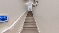 Located at 10340 S Decatur Blvd in Las Vegas, Nevada, this thoughtfully designed one-bedroom, one-bathroom residence offers a comfortable and functional layout across a single floor. A carpeted staircase with a white handrail and decorative gold wall art serves as a welcoming entry point into the home.

The kitchen is a standout feature, showcasing crisp white shaker cabinetry with brushed nickel hardware, light wood-look flooring, subway tile backsplash, and stainless steel appliances including a range, built-in microwave, and French door refrigerator. A kitchen island with seating adds versatility for dining and entertaining.

The open living area flows seamlessly toward a sliding glass door that leads to a private balcony, offering outdoor views and natural light. The bedroom provides a cozy retreat with plush carpeting, a ceiling fan, and natural light from a window. A dedicated closet and hallway connect the living spaces efficiently.

The bathroom features a soaking tub and shower combination with a rainfall showerhead, clean tile flooring, and white vanity cabinetry. A separate laundry room houses a full-size Whirlpool washer and dryer, adding everyday convenience. The overall ambiance is modern, warm, and well-appointed throughout.