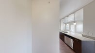 This thoughtfully designed single-floor residence offers three bedrooms and three full bathrooms across a comfortable and functional layout. The open-concept kitchen and living area serves as the heart of the home, featuring a galley-style kitchen outfitted with dark espresso cabinetry, granite countertops, stainless steel appliances including a refrigerator, range, and built-in microwave, and a white subway tile backsplash. Track lighting and pendant fixtures illuminate the space effectively. The living area adjoins the kitchen and features warm hardwood-style flooring, a ceiling fan, and multiple windows that invite natural light. Each of the three bedrooms is carpeted and equipped with a ceiling fan. The primary bedroom is a well-proportioned retreat with corner windows on two walls, providing ample natural light and outdoor views. Additional bedrooms offer similar comfort, each with access to natural light. Two closets are included in the floor plan, with at least one featuring built-in shelving and hanging rods. The three bathrooms are finished with granite-topped dark wood vanities, hardwood-style flooring, and clean white fixtures, with at least one bath including a full soaking tub with shower. The overall aesthetic is modern and neutral throughout.
