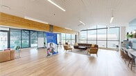 Located at 914 S Milton Rd in Flagstaff, Arizona, this thoughtfully designed single-floor space offers a generous and versatile layout across its approximately 2,040 square feet. The interior showcases a modern aesthetic defined by light hardwood flooring, white slatted ceilings, and an abundance of natural light streaming through expansive floor-to-ceiling windows. These large-scale windows frame striking panoramic views of Flagstaff's surrounding mountains and cityscape, creating a bright and energizing atmosphere throughout.

The open main area serves as the heart of the space, featuring a comfortable lounge zone with leather seating, a large coffee table, and ample room for gathering. Adjacent to this is a collaborative work area outfitted with high-top tables and vibrant teal bar stools set against a dramatic topographic mural wall — a standout design element that adds artistic character. A service counter with a teal tile backsplash, computer workstations, and a vending machine provide practical amenities for daily use.

Smaller private rooms offer a quieter retreat, each furnished with cushioned chairs, a marble-top accent table, a wall-mounted display screen, and a clerestory window for added light. Mobile whiteboard dividers in the flexible work zone allow for adaptable configurations. The overall ambiance blends functionality with an inviting, contemporary warmth suited for community and professional use.