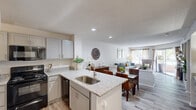 Located at 5489 Crescent Ridge Dr in Dublin, Ohio, this single-floor, 2-bedroom, 2-bathroom home offers a thoughtfully designed open-concept layout. The kitchen serves as a central hub, showcasing granite-look countertops, a peninsula with an undermount sink, gray cabinetry, wood-look flooring, and black appliances including a range and dishwasher. Recessed lighting enhances the bright, airy feel as the kitchen flows seamlessly into the dining area and living room. The living room is a comfortable retreat, highlighted by a wood-burning fireplace, large windows, and a sliding glass door that opens to a private patio with outdoor views of mature trees. The primary bedroom features plush carpeting, a natural light-filled window, and access to a spacious walk-in closet with wire shelving. The second bedroom is similarly well-sized with its own closet. Both bathrooms are finished with light wood-look flooring, white vanities, and tub-shower combinations with tile surrounds. A hallway connects the private quarters, and two closets provide ample storage throughout. The home's neutral color palette and consistent finishes create a cohesive, move-in-ready ambiance.