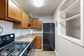 Located at 14801 Bowie Rd in Laurel, MD, this single-floor unit offers a well-organized layout across three bedrooms and two bathrooms. The living room is a standout space, featuring large sliding glass doors that span nearly the full width of the wall, providing abundant natural light and direct access to a balcony overlooking mature trees. Neutral-toned carpet and clean white walls give the living area a bright, open feel.

The kitchen is equipped with warm-toned wood cabinetry, granite-style countertops, a gas range, and a full-size refrigerator, all finished in black. Light wood-style flooring runs throughout the kitchen, which opens conveniently into the main living area.

Each of the three bedrooms features plush carpeting and windows that allow natural light to filter in. The primary bedroom includes a set of louvered bi-fold closet doors offering generous storage. The secondary bedrooms are similarly carpeted with neutral walls.

The two bathrooms are cleanly finished; one features a tub-shower combo with tile surround accented by a decorative mosaic border, while the other includes a granite-top vanity with a medicine cabinet mirror.