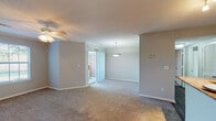 This single-story, one-bedroom, one-bathroom unit offers a well-organized layout designed to maximize functionality. The open-concept living and dining area is finished with neutral-toned carpet and features crown molding, a ceiling fan with light kit, and a pendant light that adds warmth to the dining space. A large window invites natural light throughout, while a sliding door provides additional access and brightness. The kitchen is a standout feature, showcasing rich dark cabinetry with brushed nickel hardware, granite-style countertops, a breakfast bar peninsula, stainless steel refrigerator, and an electric range—all accented by track lighting and wood-look hard flooring that extends through the kitchen and entry areas. The bedroom is generously proportioned, offering plush carpeting, a ceiling fan with light, a walk-in closet, and direct access to additional storage. The bathroom is neatly finished with a dark vanity topped with granite-style counters, a tub-shower combination with a curved curtain rod, and durable wood-look flooring. Neutral gray walls throughout give the space a cohesive, modern feel.