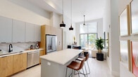 Located at 8401 NW 35th St in Doral, FL, this thoughtfully designed 2-bedroom, 3-bathroom residence offers a seamless blend of contemporary style and functional living across a single floor. The open-concept living and kitchen area is immediately striking, boasting soaring ceilings, light wood-look tile flooring, and floor-to-ceiling sliding glass doors that flood the space with natural light and open to a private balcony overlooking lush tropical greenery. The kitchen is appointed with warm wood cabinetry, a marble-style backsplash, quartz countertops, stainless steel appliances, and a generous island with bar seating — ideal for both everyday living and entertaining. The living area features dramatic ceiling height, creating an airy, expansive ambiance. Both bedrooms are bright and serene, with the primary suite offering a well-appointed walk-in closet and direct access to a private bathroom. An additional walk-in style closet area provides flexible storage. The bathrooms are finished in clean, modern palettes with glass-enclosed showers and black hardware accents. The private balcony, framed by mature trees and tropical landscaping, offers a tranquil outdoor retreat in the heart of Doral.