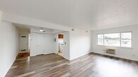 This 2-bedroom, 1-bathroom residence at 21831 Libby Rd in Bedford Heights, Ohio offers a practical, well-organized single-floor layout. The open living and dining area features wood-look laminate flooring and crisp white walls, creating a bright, clean atmosphere. Natural light flows in through multiple windows, and a ceiling fan adds comfort to the space. The entry door features warm wood tones that complement the flooring throughout the common areas.

The kitchen is equipped with warm-toned wood cabinetry, dark granite-style countertops, a double sink, a gas range, and a full-size refrigerator. Light ceramic tile flooring and a window above the sink bring functionality and brightness to the cooking space.

Both bedrooms are carpeted for comfort and each includes a ceiling fan with light fixture and a closet. The primary bedroom features dual windows offering natural light and neighborhood views, while the second bedroom includes a wall-mounted window AC unit. The home boasts a total of five closets, providing generous storage throughout.

The full bathroom features white tile walls, a tub/shower combination, a vanity with storage, and light tile flooring. A hallway connects the main living areas to the bedrooms and bathroom, ensuring a logical and efficient flow throughout the home.