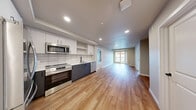 Located at 991 118th Ave SE in Bellevue, WA, this 2-bedroom, 2-bathroom residence offers a thoughtfully designed single-floor layout with modern finishes throughout. The open-concept kitchen and living area is anchored by warm luxury vinyl plank flooring, recessed lighting, and a seamless flow toward the private balcony, which brings in natural light through a glass-paned door. The kitchen is well-appointed with white upper cabinetry, dark lower cabinets, a subway tile backsplash, and a full suite of stainless steel appliances including a refrigerator, electric range, microwave, and dishwasher. The primary bedroom offers a comfortable footprint with plush carpeting, a large window overlooking greenery, and access to a dedicated walk-in closet with wire shelving. The second bedroom also features carpet flooring and ample wall space, with its own closet nearby. Both bathrooms are finished with tile flooring and clean, contemporary fixtures; one includes a walk-in shower with built-in shelving and dark hardware accents. A dedicated laundry area houses a stacked washer and dryer unit. Neutral wall tones and consistent trim details unify the space, creating a clean and functional living environment.