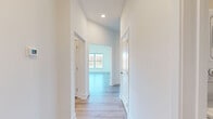 Located in Stevensville, MD, this thoughtfully designed 2-bedroom, 2-bathroom residence offers a clean, modern aesthetic across a single floor. The open-concept kitchen is a standout feature, equipped with stainless steel appliances including a refrigerator, electric range, and built-in microwave. White shaker cabinetry, a light quartz peninsula, and a slate-blue subway tile backsplash complete the space, all set atop light-toned hardwood-style flooring. Wide hallways connect the rooms seamlessly, with recessed lighting and crisp white walls creating a bright, airy atmosphere throughout.

Both bedrooms feature plush carpet flooring and large windows that invite natural light and offer views of the surrounding landscape. The spacious primary bedroom provides a comfortable retreat, while the second bedroom offers comparable comfort and natural light. The two bathrooms mirror each other in design, each featuring large-format gray tile in the tub/shower surrounds, matching tile flooring, white vanities with elegant marble-look countertops, and brushed nickel fixtures. Additional spaces include a closet, utility room, and multiple hallways that contribute to the home's efficient and functional layout.