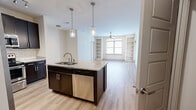 Located at 300 State St in downtown Knoxville, TN, this well-appointed 2-bedroom, 2-bathroom residence offers a thoughtfully designed single-floor layout. The open-concept kitchen, dining, and living area forms the heart of the home, anchored by a central island with a granite countertop, undermount sink, and stainless steel dishwasher. The kitchen features rich dark cabinetry reaching to the ceiling, a white subway tile backsplash, stainless steel appliances including a French door refrigerator and microwave, and track and pendant lighting. Light hardwood-style flooring flows throughout the main living areas, complementing the neutral color palette. The spacious living room is highlighted by a ceiling fan, built-in shelving flanking the windows, and a glass-panel door providing natural light. Both bedrooms are carpeted and include ceiling fans; the primary bedroom offers dual windows with outdoor views, while the second bedroom features its own window. The bathrooms include granite vanity countertops and a tub-shower with classic white subway tile surround. Additional features include a dedicated dining area, hallways, and a closet for storage. The overall ambiance is clean, modern, and move-in ready.