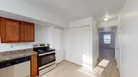 This two-floor space is designed with a clean, straightforward layout that prioritizes functionality and natural light. Light wood-style flooring runs consistently throughout, creating a cohesive and airy feel across all rooms.

The kitchen is well-equipped, featuring warm-toned wooden cabinetry, granite-style countertops, and stainless steel appliances including an electric range, dishwasher, and refrigerator. A built-in sink and additional storage are neatly integrated into the L-shaped layout. Adjacent to the kitchen, a set of louvered bifold doors provides convenient pantry or utility storage.

The living and bedroom areas are bright and open, benefiting from multiple windows that allow natural light to fill the spaces throughout the day. Neutral white walls complement the light flooring, lending a versatile backdrop suitable for various interior styles. Several rooms include sliding or bifold closets, offering practical built-in storage solutions.

The bathroom is clean and simply appointed, with essential fixtures and a chrome towel bar. A central hallway connects the rooms efficiently, as visible in the overhead layout view, which reveals a well-organized and functional floor plan overall.