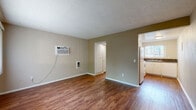 Located at 154 N Palmetto Ave in Ontario, CA, this efficient single-floor unit is thoughtfully laid out to make the most of its compact footprint. The living room serves as the heart of the space, featuring rich hardwood-style flooring, neutral beige walls, and a textured ceiling. A large window dressed with vertical blinds allows natural light to fill the room, while a wall-mounted air conditioning unit and a wall heater provide year-round climate control. The living area connects seamlessly via a hallway to the rest of the unit. The kitchen is well-appointed with white cabinetry, dark granite-style countertops, a double stainless steel sink, a white electric range, and an over-the-range microwave. A window above the sink brings in additional natural light and outdoor views. The bathroom is clean and functional, featuring a toilet, vanity, towel bar, and a high window that provides ventilation and natural light. Two closets offer practical storage solutions, while a dedicated utility room adds further functionality. Consistent hardwood-style flooring runs throughout, tying the space together with a warm, cohesive aesthetic.