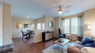 This well-appointed 1-bedroom, 1-bathroom residence delivers a comfortable and functional single-floor layout with a warm, neutral color palette throughout. Rich hardwood flooring flows through the main living areas, anchoring an open-concept design that connects the living room, dining area, and kitchen seamlessly. The living room is bright and inviting, featuring a ceiling fan, large windows with plantation blinds that welcome natural light, and an arched pass-through that frames the kitchen beyond. The kitchen is well-equipped with dark espresso cabinetry, granite-style countertops, stainless steel appliances including a range, microwave, and dishwasher, plus a breakfast bar with seating. The dining area is a defined yet open space with wainscoting detail, a wall of mirrors, and access to an exterior door. The bedroom offers a calm retreat with plush carpet, a ceiling fan, natural light from window treatments, and ample space for a full furniture arrangement. The bathroom features tile flooring, dark vanity cabinetry with granite counters, a large mirror, and generous counter space. Together, these elements create a cohesive, comfortable living environment with practical finishes and a refined aesthetic throughout.