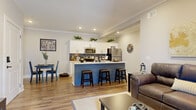 This single-story, 3-bedroom, 2-bathroom home in Columbia, SC offers a thoughtfully designed open-concept layout with modern finishes and a cohesive aesthetic throughout. Wide-plank hardwood-style flooring flows seamlessly across all living areas, complemented by crown molding and recessed lighting that add a polished touch.

The kitchen is a standout feature, boasting white shaker cabinetry, a bold blue subway tile backsplash, stainless steel appliances, and a large center island with bar seating — perfect for casual dining or entertaining. The kitchen opens directly to a bright living room with a glass exterior door that invites natural light, and a defined dining area accented by geometric wall shelving.

The primary bedroom offers a comfortable, well-proportioned retreat, while two additional bedrooms provide flexible space for guests or a home office. The bathrooms feature white shaker cabinetry with dark hardware, white countertops, and a full-length arched mirror adding a sophisticated design element. The clean, neutral color palette throughout — soft whites and warm greiges — creates a calm and inviting ambiance that makes the entire home feel open, modern, and move-in ready.