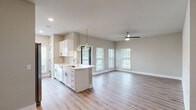 Located on Johns Island, SC, this single-story home offers a thoughtfully designed open-concept floor plan with modern finishes throughout. Light-toned luxury vinyl plank flooring flows seamlessly across every room, complementing the neutral warm-gray palette that creates a clean and cohesive aesthetic.

The kitchen serves as the centerpiece of the living area, featuring white shaker-style cabinetry, a kitchen island with a built-in sink and pendant lighting overhead, stainless steel appliances, and a decorative wine rack. The kitchen opens directly into the spacious living area, which is equipped with a ceiling fan and multiple windows that allow abundant natural light.

A well-lit hallway with stylish gray panel doors connects the main living area to the private rooms. The bedrooms are generously sized, each featuring ceiling fans and windows with views of the surrounding greenery. The primary bathroom is appointed with a dual-sink white vanity, quartz countertops, large mirrors with modern light fixtures, and a tiled shower. A secondary bathroom mirrors the same clean, white design. The dedicated laundry room includes a full-size washer and dryer with built-in overhead shelving, adding practical convenience to this well-appointed home.