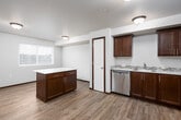 This single-floor unit offers a thoughtfully designed layout that balances functionality and comfort. The open-concept living and kitchen area is anchored by warm hardwood-style flooring that flows throughout the main spaces, creating a cohesive and inviting atmosphere. A wide hallway connects the living area to the kitchen, providing an easy sense of flow between the two spaces.

The kitchen is a standout feature, equipped with rich dark-toned cabinetry, light stone-look countertops with a subtle tile backsplash accent, and a full suite of stainless steel appliances, including a refrigerator, electric range, microwave, and dishwasher. Ample upper and lower cabinet storage ensures practical everyday use. A pantry closet adds additional storage conveniently accessible from the kitchen.

The bedrooms are carpeted for comfort and include closet space and windows that allow natural light. The neutral wall tones throughout create a clean, versatile backdrop suitable for various décor styles.

The bathroom features a granite-look vanity countertop, a full tub-shower combination, and wood-toned cabinetry. A dedicated laundry area with a stacked washer and dryer unit is conveniently integrated within the unit, adding everyday practicality to the overall design.