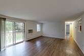 Located at 8 Cedar Pond Dr in Warwick, Rhode Island, this single-floor, two-bedroom, two-bathroom residence offers a practical and comfortable layout. Rich hardwood-style flooring runs throughout the living areas, complementing the clean white walls and textured ceilings found across much of the home. The spacious living room is bathed in natural light from large sliding glass doors that open onto a private balcony with views of lush greenery, alongside an additional window and a wall-mounted air conditioning unit. A dedicated dining area flows naturally from the living space, providing a well-defined area for meals and entertaining. The kitchen is well-appointed with rich cherry-toned cabinetry, dark countertops, and a full suite of stainless steel appliances including a refrigerator, dishwasher, and range, all set on light hardwood-style flooring. A pantry offers additional storage convenience. The generously sized primary bedroom features its own window with outdoor views, a wall AC unit, and baseboard heating. The second bedroom is bright and airy, with a large window and hardwood-style floors. Both bathrooms are clean and functional, with one featuring a tiled shower-tub combination. Four closets throughout the unit ensure abundant storage.