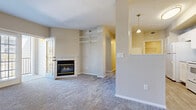 This single-floor residence offers a well-organized layout designed for comfortable everyday living. The living room serves as the central gathering space, finished with plush carpeting and anchored by a tile-surround gas fireplace. French doors with shuttered windows open directly onto a private balcony, allowing natural light to fill the room. Built-in shelving flanks the fireplace wall, providing convenient display and storage options. A half-wall with a pass-through opening connects the living area to the kitchen, maintaining an open feel while defining each space.

The galley-style kitchen is fitted with white cabinetry, grey laminate countertops, a subway tile backsplash, and white appliances including a range, overhead microwave, refrigerator, and dishwasher. Wood-look vinyl flooring runs throughout the kitchen and extends into the bathroom, which features a tiled tub-shower combination, a white vanity with brushed nickel hardware, and matching flooring. A dedicated laundry room houses a full-size top-load washer and dryer with overhead wire shelving.

The bedrooms are carpeted and receive natural light through sizable windows with blinds. Each room offers a quiet, neutral atmosphere well-suited for rest.