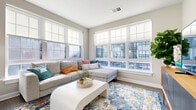 Located at 644 Chlois Ln in Columbus, OH, this single-floor residence combines modern design with comfortable, functional living spaces throughout. The living room serves as a standout centerpiece, wrapped on two sides by large multi-pane windows fitted with roller shades that bathe the space in abundant natural light and offer views of the surrounding urban streetscape. Wide-plank hardwood-style flooring runs throughout the main living areas, anchoring the open, airy feel of the home.

The kitchen is thoughtfully designed with rich warm-toned cabinetry, a light tile backsplash, stainless steel appliances, and a generous island with bar seating — ideal for casual dining or entertaining. Pendant lighting adds a polished finishing touch above the island.

The bedroom features plush carpeting, a bold teal accent wall, and a sliding barn door that lends a contemporary aesthetic. A spacious walk-in closet with wire shelving provides ample storage. The en-suite bathroom includes hardwood-style flooring, a wood-toned vanity with a white countertop, a framed mirror, and a glass-enclosed shower. A separate half bath with a pedestal sink and hardwood-style flooring rounds out the layout, offering added convenience for guests.