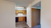 Located at 421 Lancaster Ave in Reynoldsburg, Ohio, this residential unit offers a practical and comfortable layout designed for everyday living. The kitchen is a standout functional space, outfitted with warm honey-toned wood cabinetry providing generous storage, a double-basin sink, and black appliances including a gas range, dishwasher, and refrigerator. Durable wood-look vinyl flooring runs throughout the kitchen, adding a clean, modern touch. Adjacent to the kitchen, a hallway connects the main living areas, with a sliding wood-panel closet door offering convenient storage access. The living room is a spacious, light-filled area featuring plush carpeting underfoot and large vertical-blind-covered windows that allow natural light to pour in. A wooden staircase with classic baluster detailing is positioned at one end of the living room, serving as both a functional and architectural element. Additional carpeted rooms provide flexible space for bedrooms or other uses. The bathroom is well-appointed with a wood-vanity cabinet, a wide mirror, a countertop sink, and wood-look flooring, maintaining a consistent design aesthetic throughout. Textured ceilings and neutral wall tones complete the interior, creating a clean and move-in-ready environment throughout the unit.