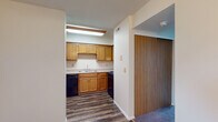 Located at 421 Lancaster Ave in Reynoldsburg, Ohio, this residential unit offers a practical and comfortable layout designed for everyday living. The kitchen is a standout functional space, outfitted with warm honey-toned wood cabinetry providing generous storage, a double-basin sink, and black appliances including a gas range, dishwasher, and refrigerator. Durable wood-look vinyl flooring runs throughout the kitchen, adding a clean, modern touch. Adjacent to the kitchen, a hallway connects the main living areas, with a sliding wood-panel closet door offering convenient storage access. The living room is a spacious, light-filled area featuring plush carpeting underfoot and large vertical-blind-covered windows that allow natural light to pour in. A wooden staircase with classic baluster detailing is positioned at one end of the living room, serving as both a functional and architectural element. Additional carpeted rooms provide flexible space for bedrooms or other uses. The bathroom is well-appointed with a wood-vanity cabinet, a wide mirror, a countertop sink, and wood-look flooring, maintaining a consistent design aesthetic throughout. Textured ceilings and neutral wall tones complete the interior, creating a clean and move-in-ready environment throughout the unit.