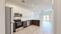 This thoughtfully designed one-bedroom, one-bathroom residence offers a modern living experience with a clean, open-concept layout. Light hardwood-style flooring flows seamlessly throughout, creating a bright and cohesive atmosphere.

The kitchen is a standout feature, boasting two-tone cabinetry with crisp white upper cabinets and dark wood-grain lower cabinets, complemented by a white subway tile backsplash and light quartz countertops. Stainless steel appliances — including a range, microwave, and dishwasher — add a polished, contemporary touch. A peninsula with an undermount sink extends the counter space and creates a natural divide between the kitchen and living area. Pendant lighting above the peninsula and a ceiling fan in the living area enhance both function and style. Sliding glass doors lead to an outdoor balcony, filling the living space with natural light.

The bedroom is a comfortable, well-proportioned retreat featuring a ceiling fan, a window with outdoor views, and direct access to a walk-in closet outfitted with built-in shelving and hanging rods for ample storage.

The bathroom is clean and functional, featuring a full soaking tub with a tiled shower surround. A hallway connects all areas of the residence efficiently, completing this well-organized and modern floor plan.