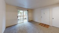 Located at 1645 Northeast 20th Street in Gresham, Oregon, this single-floor, one-bedroom, one-bathroom residence offers a practical and comfortable layout. The living area is carpeted and bright, featuring a ceiling fan and a sliding glass door that opens to a private balcony with views of surrounding greenery, filling the space with natural light. A front entry door with hardwood-style flooring transitions seamlessly into the carpeted living area. The kitchen is designed in a galley style with light wood cabinetry, laminate countertops, hardwood-style flooring, and white appliances including a refrigerator, electric range, and dishwasher. A pass-through counter connects the kitchen to the living space, enhancing the open feel. The bedroom is generously sized with carpet flooring, a sliding-door closet for storage, and its own sliding glass door leading to the balcony. The full bathroom features a tub/shower combination, a single-sink vanity with light wood cabinetry, and hardwood-style flooring. A dedicated laundry area includes a full-size washer and dryer with overhead shelving. Neutral tones throughout create a clean, cohesive aesthetic ideal for comfortable everyday living.
