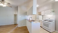 Located at 5217 Adolphus Ave in El Paso, TX, this single-story 2-bedroom, 1-bathroom home offers a well-organized and functional layout. The combined kitchen and living area forms the heart of the home, featuring warm hardwood-style flooring, a ceiling fan, and a wall-mounted heater. The kitchen is highlighted by a peninsula with a dark wood countertop and double-basin sink, classic white cabinetry with open shelving, a subway tile backsplash, tile flooring, and white gas range and refrigerator. Both bedrooms are carpeted and include ceiling fans with light fixtures and windows that let in natural light with views of surrounding greenery. The primary bedroom offers a comfortable, quiet retreat. Two closets provide convenient storage throughout the home. The bathroom is finished with tile flooring, a tub/shower combination with full tile surround, a granite-topped vanity, and a clean, neutral palette. A hallway connects the main living areas efficiently. The overall aesthetic is clean and neutral, with light-toned walls throughout that create a bright, move-in ready atmosphere well-suited for everyday living.