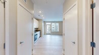 Located at 509 W Rich St in Columbus, Ohio, this efficiently designed single-floor unit offers a clean, modern aesthetic with a thoughtful layout. Light-toned hardwood flooring runs throughout the space, creating a cohesive and airy feel.

The kitchen is a standout feature, outfitted with a full suite of stainless steel appliances including a refrigerator, electric range, over-the-range microwave, and dishwasher. Crisp white shaker-style cabinetry extends to the ceiling, maximizing storage, while a sleek countertop with an undermount sink completes the functional workspace.

The open living area is bright and minimalist, with neutral walls, recessed lighting, and a visible electrical panel along one wall. A glass-paned door leads to a private outdoor balcony with metal railing — a welcome extension of the living space with outdoor views.

The bathroom is well-appointed with a white vanity, a glass-enclosed shower, and light hardwood-style flooring that carries the design language of the rest of the unit. Brushed nickel fixtures and clean taupe walls give the space a polished, contemporary finish.

Overall, this unit presents a modern, move-in-ready space with quality finishes, practical storage solutions, and a consistent design sensibility throughout.