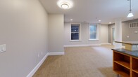 Located at 846 Main St in Buffalo, NY, this 2-bedroom, 3-bathroom residence offers a thoughtfully arranged single-floor layout with a cohesive blend of modern and functional design. The open-concept kitchen features light wood cabinetry, stainless steel appliances including a refrigerator and microwave, a gas range, and a peninsula with granite-style countertops and pendant lighting overhead — seamlessly connecting to the main living area finished with neutral carpeting and recessed lighting throughout.

The primary bedroom is generously proportioned, featuring dual windows that bring in natural light and offer pleasant views of surrounding greenery. The second bedroom is also well-sized, with carpeted flooring and recessed lighting. Both rooms are finished with clean neutral tones and crisp white baseboards.

The bathrooms are elegantly appointed, showcasing large-format white tile flooring, dark granite countertops, warm wood vanities with ample drawer storage, and framed mirrors. One bathroom features a glass-enclosed walk-in shower with mosaic tile accents and built-in open wood shelving for added storage.

A dedicated laundry room houses a full-size washer and dryer alongside mechanical systems. A hallway connects the living spaces, completing this well-equipped and move-in-ready Buffalo residence.