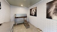Located in Hoover, Alabama, this purpose-built pet grooming room is a compact yet fully equipped space designed with both function and style in mind. The walls are clad floor-to-ceiling in crisp white subway tile, lending the room a clean, hygienic aesthetic that is easy to maintain. Underfoot, classic hexagonal floor tiles add a timeless design touch while providing a durable, slip-resistant surface.

The centerpiece of the room is a professional-grade stainless steel pet wash tub, complete with a handheld spray nozzle and a step ramp for easy pet access. Adjacent to the tub, a stainless steel grooming table provides a dedicated workspace for drying and finishing. A trash receptacle is conveniently positioned nearby, and multiple electrical outlets accommodate grooming tools such as dryers and clippers.

The muted sage-green ceiling provides a subtle contrast to the bright white walls, contributing to a calm and welcoming atmosphere. A glass-paned entry door floods the space with natural light and offers a view to an outdoor terrace, enhancing the room's openness. Two striking large-format black-and-white photographic prints of dogs adorn the walls, reinforcing the space's devoted canine character. Recessed ceiling lighting ensures the room is well-illuminated for grooming tasks.