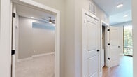 Located at 350 Carraway Crossing in Chapel Hill, NC, this well-designed one-bedroom, one-bathroom residence offers a thoughtful single-floor layout that maximizes every square foot. The kitchen is a standout feature, outfitted with crisp white shaker-style cabinetry extending to the ceiling, stainless steel appliances including a French door refrigerator, microwave, and range, clean white countertops, and light hardwood flooring. A floor-to-ceiling window floods the kitchen with natural light and frames pleasant outdoor views of the surrounding greenery and community. A hallway connects the living areas to the private quarters, where the carpeted bedroom offers a calm, neutral palette, a ceiling fan, and recessed lighting. The bedroom includes access to a dedicated closet with built-in hanging rods, providing organized storage. The bathroom features a soaking tub with a shower overhead, accented by large-format marble-look tile surround, lending a clean and contemporary feel. Throughout the residence, neutral tones, recessed lighting, and crisp white trim create a cohesive, modern aesthetic that is both functional and inviting.