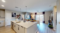 This well-designed single-floor residence offers a seamless blend of modern style and functional living across its thoughtfully arranged layout. The heart of the home is a striking open-concept kitchen, dining, and living area that flows effortlessly together. The kitchen is appointed with crisp white shaker cabinetry, quartz countertops, a large center island with bar seating and an undermount sink, stainless steel appliances, and a tasteful tile backsplash — all set above light hardwood flooring. Pendant lighting above the island adds a contemporary touch. The living area extends naturally from the kitchen, featuring a ceiling fan and large sliding glass doors that open to a private balcony, allowing an abundance of natural light and outdoor views. The primary bedroom is a comfortable retreat with plush carpeting, a ceiling fan, and a bold accent wall. Its en-suite bathroom offers a wide quartz vanity with white cabinetry, illuminated mirror, and a walk-in closet. A second bedroom mirrors the same cozy, carpeted comfort with ample natural light. The second bathroom echoes the same refined finishes, featuring matching white cabinetry and quartz surfaces. Neutral tones throughout create a cohesive, welcoming ambiance.