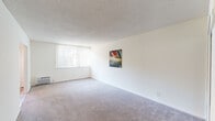 Located at 6920 Sepulveda Blvd in the Van Nuys neighborhood of Los Angeles, this single-floor unit offers a clean, functional layout with a neutral palette throughout. The living area is generously proportioned, featuring wall-to-wall carpeting, a textured ceiling, and a large window dressed with vertical blinds that allows natural light to fill the room. A wall-mounted piece of abstract artwork adds a touch of color to the otherwise bright, white walls.

The kitchen is efficiently designed with crisp white Shaker-style cabinetry extending from floor to ceiling, offering ample storage. It is equipped with a double-basin stainless steel sink, a gas range with an overhead exhaust hood, and a full-size refrigerator. Light wood-style flooring runs throughout the kitchen, creating a clean and easy-to-maintain surface.

The bedroom features mirrored sliding closet doors that enhance the sense of space and reflect natural light from the adjacent window. A second carpeted area adjacent to the living space provides additional flexibility.

The bathroom is neatly appointed with light wood-look tile flooring, a white vanity with a grey countertop, a mirrored medicine cabinet, and a full bathtub. The overall ambiance of the unit is light, airy, and move-in ready, with a straightforward design suited for comfortable everyday living.