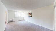 Located at 6920 Sepulveda Blvd in the Van Nuys neighborhood of Los Angeles, this single-floor unit offers a clean, functional layout with a neutral palette throughout. The living area is generously proportioned, featuring wall-to-wall carpeting, a textured ceiling, and a large window dressed with vertical blinds that allows natural light to fill the room. A wall-mounted piece of abstract artwork adds a touch of color to the otherwise bright, white walls.

The kitchen is efficiently designed with crisp white Shaker-style cabinetry extending from floor to ceiling, offering ample storage. It is equipped with a double-basin stainless steel sink, a gas range with an overhead exhaust hood, and a full-size refrigerator. Light wood-style flooring runs throughout the kitchen, creating a clean and easy-to-maintain surface.

The bedroom features mirrored sliding closet doors that enhance the sense of space and reflect natural light from the adjacent window. A second carpeted area adjacent to the living space provides additional flexibility.

The bathroom is neatly appointed with light wood-look tile flooring, a white vanity with a grey countertop, a mirrored medicine cabinet, and a full bathtub. The overall ambiance of the unit is light, airy, and move-in ready, with a straightforward design suited for comfortable everyday living.
