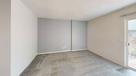 Located at 10510 SW Butner Rd in Portland, Oregon, this two-bedroom, two-bathroom apartment is thoughtfully laid out across two equally sized floors, offering a practical and comfortable living arrangement. The main level features a combined living and dining area filled with natural light from a large sliding glass door that frames views of surrounding greenery. The kitchen is equipped with white cabinetry, laminate countertops, a coil-top electric range, refrigerator, and a peninsula that provides additional prep space and casual seating. Wood-style flooring runs through the entry, hallways, kitchen, and bathrooms, while soft carpet covers the living and bedroom areas. Two staircases connect the floors, with hallways guiding traffic efficiently between rooms. Both bedrooms are generously sized, with the primary bedroom featuring dual closets and direct access to a full bathroom with a vanity, mirror cabinet, and granite-style countertop. The second bedroom benefits from a large window overlooking lush outdoor foliage. Five closets distributed throughout the unit provide substantial storage. Textured ceilings are present throughout, adding a classic residential character. The unit offers a well-balanced blend of functionality and comfort in a green, tree-lined Portland neighborhood.