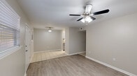 This single-story home in Baton Rouge, Louisiana offers a efficiently organized layout comprising four bedrooms, two bathrooms, a living room, kitchen, hallway, and closet. The open living area features light wood-look laminate flooring and a ceiling fan with integrated lighting, flowing seamlessly into a dining or secondary living zone finished with neutral tile flooring. A pendant light marks the transition toward the kitchen, which is appointed with gray cabinetry, granite-look countertops, a stainless steel double sink, and matching stainless appliances including a refrigerator and range.

A central hallway connects the bedrooms, each finished with wood-look flooring, ceiling fans, and window blinds that allow natural light. Several bedrooms include closets with built-in rods for storage. The bathrooms feature tile flooring, gray vanities with granite-look countertops, and framed mirrors. One bathroom includes a tub-shower combination with tiled surround, while the other offers a shower and a small window for ventilation. Neutral warm-gray walls throughout create a cohesive, understated aesthetic.