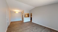 Located in the Ashton Brook community in Louisville, KY, this single-floor unit offers a thoughtfully designed layout with a mix of modern finishes and practical conveniences. The living area is highlighted by vaulted ceilings that lend a sense of openness and volume to the space, complemented by rich, dark hardwood-style flooring and neutral gray walls. A sliding glass door allows natural light to pour in while providing access to the outdoors. The kitchen connects to the living area through a convenient pass-through window, creating a semi-open feel. It features granite-style countertops, gray cabinetry with sleek bar-pull hardware, a stainless steel sink, and stainless steel appliances including a dishwasher and refrigerator. The bedroom is carpeted for comfort and includes a window with outdoor views, as well as a closet that houses a stacked washer and dryer unit — a practical in-unit laundry solution. The bathroom is clean and functional, with wood-look tile flooring, granite-topped vanity, and accessibility-friendly grab bars. Textured ceilings throughout add a classic character to the home, while the consistent neutral palette creates a cohesive and move-in-ready aesthetic throughout the entire unit.