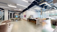 This thoughtfully designed single-floor commercial space offers a dynamic and versatile environment that seamlessly blends functionality with modern aesthetics. The open-plan layout is anchored by a striking kitchen and lounge area featuring a dramatic marble-topped island with bar seating, warm wood cabinetry, and stainless steel appliances. A ventilation hood, pendant lighting, and polished concrete floors add an industrial-chic character throughout.

The space is divided into distinct yet connected zones, including a comfortable lounge area furnished with plush, curved seating and large floor-to-ceiling windows that flood the interior with natural light and offer views to the street. A bold navy-painted exposed ceiling with visible ductwork contrasts elegantly with the bright white walls and linear LED lighting.

Glass-partitioned rooms line the perimeter, providing private meeting or office areas while maintaining a sense of openness. A recreation zone features a billiards table set atop a colorful, graphic-patterned floor inlay. An entry area showcases rich green marble-patterned flooring, wood credenzas with stone countertops, and curated original artwork. Open metal shelving adds an organized, editorial touch to a lounge nook. Together, these elements create a vibrant, amenity-rich environment well-suited for collaborative and social engagement.