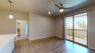This single-floor residence offers a thoughtfully designed layout that balances comfort and functionality throughout. The living areas feature durable wood-look flooring, neutral-toned walls, and ceiling fans with integrated lighting, creating a bright and airy atmosphere. Sliding glass doors in multiple rooms connect the interior to an outdoor balcony, allowing natural light to flow in while offering views of the surrounding area.

The kitchen is a standout space, showcasing rich, dark wood-grain cabinetry extending to the upper walls, contrasted by crisp white countertops and a subtle tile backsplash. Black appliances, including a range and over-the-range microwave, complete the sleek, modern aesthetic. Light wood-look flooring ties the kitchen together seamlessly.

The bedrooms are generously sized and carpeted for warmth and comfort. Each room features ceiling fans, ample natural light through windows with blinds, and convenient access to the rest of the home.

Two well-appointed bathrooms serve the residence. One includes a combined tub and shower with clean white fixtures, while the other features a walk-in glass-door shower, a vanity with a bold navy cabinetry finish, and wood-look flooring—adding a distinctive design element to the space. Both bathrooms maintain a clean, modern aesthetic with white countertops and large mirrors.