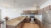 Located in Spokane Valley, WA, this single-floor, 3-bedroom, 2-bathroom residence offers a well-designed layout that maximizes functionality and comfort. The open-concept living, dining, and kitchen area serves as the heart of the home, bathed in natural light through large windows that lead out to a private patio overlooking a well-maintained community exterior. The living and dining space features light wood-tone flooring, neutral walls, and a clean, modern aesthetic.

The kitchen is a standout feature, boasting rich dark cabinetry, granite countertops, a subway tile backsplash, stainless steel appliances including a range, microwave, dishwasher, and refrigerator, and pendant lighting above the counter—combining style with practicality.

The three bedrooms offer comfortable retreats, with the primary bedroom providing a generous footprint and access to ample closet space. Five closets throughout the unit ensure abundant storage. The two bathrooms are finished with dark wood vanities, light countertops, and wood-look flooring, maintaining the home's cohesive modern design.

A dedicated in-unit laundry room with a full-size washer and dryer adds everyday convenience. The covered patio provides an outdoor extension of the living space with views of the community grounds and covered parking area.