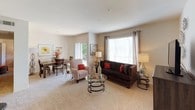 This single-floor residence offers a thoughtfully designed layout that balances comfort and functionality throughout. The open-concept living and dining area forms the heart of the home, filled with natural light streaming through large windows dressed with elegant curtains. Plush wall-to-wall carpeting adds warmth underfoot, while neutral toned walls create a versatile backdrop throughout the space.

The living area provides generous room for seating and entertaining, with easy sightlines into the adjacent dining space. The dining area features an intimate setting highlighted by warm wood furnishings and tasteful wall art, making it ideal for both everyday meals and hosting guests.

The kitchen is efficiently laid out with light wood cabinetry, white appliances including a full-size refrigerator, and durable hard-surface flooring. A dedicated walk-in pantry provides excellent storage and organization.

The bedroom is a serene retreat, offering ample space, soft carpeting, and a ceiling fan for year-round comfort. A walk-in closet offers generous storage, and large windows allow natural light and outdoor views to enhance the room's airy feel.

The bathroom is clean and functional, featuring a full soaking tub with shower, a wide vanity with storage, and wood-look flooring that adds a contemporary touch. Throughout the residence, the cohesive design and warm finishes create an inviting and comfortable living environment.