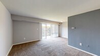 Located at 5237 Marlboro Pike in Capitol Heights, Maryland, this one-bedroom, one-bathroom residence offers a thoughtfully organized single-floor layout. The living room is a bright, open space finished with wall-to-wall carpeting and neutral-toned walls, highlighted by a bold blue-gray accent wall. Large sliding glass doors flood the room with natural light and open directly onto a private balcony, providing outdoor views of the surrounding community. The kitchen features a galley-style design with warm wood cabinetry, dark granite-style countertops, light tile flooring, and black appliances including a gas range and refrigerator — offering a functional and attractive cooking space. The spacious bedroom is carpeted and filled with natural light from a large window, with easy access to a dedicated closet for storage. The bathroom is well-finished, showcasing a full tub-shower combination clad in large-format beige tiles accented by a decorative mosaic border, complemented by polished chrome fixtures. Throughout the residence, clean white trim, neutral wall colors, and consistent carpet flooring create a cohesive and move-in-ready atmosphere.