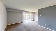 Located at 5237 Marlboro Pike in Capitol Heights, Maryland, this one-bedroom, one-bathroom residence offers a thoughtfully organized single-floor layout. The living room is a bright, open space finished with wall-to-wall carpeting and neutral-toned walls, highlighted by a bold blue-gray accent wall. Large sliding glass doors flood the room with natural light and open directly onto a private balcony, providing outdoor views of the surrounding community. The kitchen features a galley-style design with warm wood cabinetry, dark granite-style countertops, light tile flooring, and black appliances including a gas range and refrigerator — offering a functional and attractive cooking space. The spacious bedroom is carpeted and filled with natural light from a large window, with easy access to a dedicated closet for storage. The bathroom is well-finished, showcasing a full tub-shower combination clad in large-format beige tiles accented by a decorative mosaic border, complemented by polished chrome fixtures. Throughout the residence, clean white trim, neutral wall colors, and consistent carpet flooring create a cohesive and move-in-ready atmosphere.