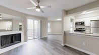 This 1-bedroom, 1-bathroom residence offers a thoughtfully designed single-floor layout that maximizes every square foot. The open-concept living and dining area is anchored by a classic fireplace and features light-toned laminate wood flooring throughout, a textured ceiling, and a ceiling fan with built-in lighting. Natural light fills the space through multiple windows and a sliding glass door that opens to a private balcony, offering outdoor views and fresh air.

The kitchen is positioned adjacent to the living area with a raised breakfast bar countertop that defines the space without enclosing it. Stainless steel appliances, including a refrigerator and range, are complemented by white cabinetry and louvered closet doors that conceal in-unit laundry or storage. The layout flows efficiently into a dedicated dining nook with additional window views.

The spacious primary bedroom is carpeted for warmth and comfort, fitted with its own ceiling fan and natural light from a large window. The full bathroom features a clean, all-white tub and shower combination, a vanity with storage, and wood-look flooring consistent with the rest of the unit. Neutral warm-gray tones throughout create a cohesive, move-in-ready ambiance.