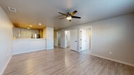 Located at 501 SW Pearl Dr in Bentonville, Arkansas, this single-floor 2-bedroom, 1-bathroom home offers a clean, modern aesthetic throughout. Light wood-look vinyl flooring runs consistently across every room, creating a cohesive and easy-to-maintain interior. Ceiling fans with integrated lighting are present in all main living areas, ensuring year-round comfort.

The open-concept living room is a generous, bright space anchored by a ceiling fan and direct access to the front entry door. It flows naturally into the kitchen, which is separated by a raised breakfast bar counter. The kitchen features gray cabinetry with modern hardware, light countertops, stainless steel appliances including an electric range, and ample upper and lower cabinet storage.

Both bedrooms are comfortably sized with neutral gray walls, ceiling fans, and large closets — the primary bedroom includes a walk-in closet alongside an additional standard closet. One bedroom features a window that brings in natural light and exterior views.

The bathroom is well-appointed with a white vanity, light countertop, and an accessible walk-in shower equipped with stainless steel grab bars — a thoughtful design detail. The overall palette of whites, grays, and warm wood tones gives the home a clean, move-in-ready feel.