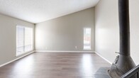 Located in Oklahoma City's 73118 zip code, this two-story, 2-bedroom, 2-bathroom home offers a well-planned layout across two floors. The main level features an open living room with durable wood-look flooring, natural light from front-facing windows, and a distinctive hanging cast-iron fireplace that serves as a bold focal point. The kitchen is well-appointed with white cabinetry, marble-look countertops, a gas range, and a striking coffered ceiling with dark wood beams, adding character to the space. A hallway connects the main living areas, and a carpeted staircase leads to the upper floor. Upstairs, two generously sized bedrooms are finished with plush carpet, ceiling fans, and natural light from windows. One bedroom features sliding glass doors opening to a private balcony, while the spacious primary bedroom includes a large walk-in closet with built-in shelving and hanging rods. The two bathrooms are functional and clean — one features a tub/shower combo with tile flooring, and the other offers a standalone glass-door shower with a marble-look vanity countertop. Throughout the home, neutral tones and textured ceilings create a consistent, comfortable aesthetic.
