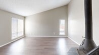 Located in Oklahoma City's 73118 zip code, this two-story, 2-bedroom, 2-bathroom home offers a well-planned layout across two floors. The main level features an open living room with durable wood-look flooring, natural light from front-facing windows, and a distinctive hanging cast-iron fireplace that serves as a bold focal point. The kitchen is well-appointed with white cabinetry, marble-look countertops, a gas range, and a striking coffered ceiling with dark wood beams, adding character to the space. A hallway connects the main living areas, and a carpeted staircase leads to the upper floor. Upstairs, two generously sized bedrooms are finished with plush carpet, ceiling fans, and natural light from windows. One bedroom features sliding glass doors opening to a private balcony, while the spacious primary bedroom includes a large walk-in closet with built-in shelving and hanging rods. The two bathrooms are functional and clean — one features a tub/shower combo with tile flooring, and the other offers a standalone glass-door shower with a marble-look vanity countertop. Throughout the home, neutral tones and textured ceilings create a consistent, comfortable aesthetic.