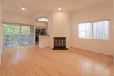 Located in the heart of Los Angeles at 7917 Selma Ave, this single-story residence offers a clean, modern aesthetic throughout. The open-concept living area is a standout feature, showcasing warm bamboo hardwood flooring that runs continuously across the space, crisp white walls, and recessed lighting that maintains a bright and airy atmosphere. A wood-burning fireplace with a sleek black surround and brass-toned doors serves as a central focal point, adding character and warmth to the living room. Sliding glass doors open to an outdoor area, inviting natural light and greenery into the interior.

The kitchen is designed in a galley layout and is equipped with stainless steel appliances including a refrigerator and range, natural wood cabinetry with frosted glass upper cabinet doors, dark countertops, and a double stainless steel sink. A skylight above the kitchen enhances brightness in this functional cooking space.

The bedroom offers generous proportions with the same bamboo flooring, recessed lighting, and a full-width mirrored sliding closet that adds depth and reflects natural light. A connecting hallway leads seamlessly between rooms, maintaining the home's cohesive, minimalist design language. The overall ambiance is clean, light-filled, and well-suited for comfortable urban living in Los Angeles.