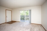 This single-floor unit offers a practical and comfortable layout designed for everyday living. The open-concept living area is anchored by plush carpeting and a ceiling fan with a built-in light fixture, creating a welcoming atmosphere. A sliding glass door leads to a private balcony, flooding the space with natural light and offering pleasant views of surrounding greenery. The transition between the living area and kitchen is marked by a shift to warm hardwood-style flooring, adding visual contrast and definition to each zone.

The kitchen is efficiently arranged in a U-shaped configuration, featuring ample white cabinetry with wood trim, generous counter space, a double-basin sink, a full-size refrigerator, and an electric range with an overhead vent hood — providing everything needed for daily meal preparation.

The bedrooms are carpeted and well-sized, each finished with textured ceilings and neutral walls. At least one bedroom includes a closet with sliding doors and built-in hanging rods, offering practical storage. Additional rooms provide flexibility for use as a bedroom, office, or guest space, with windows that invite natural light.

The bathroom is clean and functional, featuring a full soaking tub with a combination showerhead, chrome fixtures, and hardwood-style flooring. Throughout the unit, warm wood-toned baseboards and door trim provide a cohesive finishing touch.