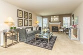 Located in Lake Orion, Michigan, this single-floor residence offers a thoughtfully designed layout that balances comfort and style. The expansive living room serves as the heart of the home, anchored by a fireplace flanked by large windows that invite natural light and open views. Plush carpeting and a seamless connection to the kitchen and dining areas create a cohesive, welcoming flow throughout.

The kitchen is outfitted with dark espresso cabinetry, granite countertops, stainless steel appliances, and wood-look tile flooring. A breakfast bar with seating connects the kitchen to the living space, making it ideal for both everyday use and entertaining. Adjacent to the kitchen, the dining area accommodates a full dining table beneath a pendant light fixture, creating a dedicated space for meals.

The bedrooms are generously proportioned, each featuring plush carpet, large windows with vertical blinds, and ample space for full bedroom suites. The primary bedroom includes sliding glass door access and an en-suite bathroom with dark vanity cabinetry, granite countertops, and a glass-enclosed shower. A second full bathroom features tile flooring, a soaking tub with tiled surround, and matching dark cabinetry. Together, these spaces deliver a refined and functional living environment.